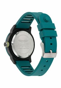 Hodinky so silikónovým remienkom v tehlovej farbe, čiernym puzdrom, strieborným nerezovým zadným dielom a okrúhlym ciferníkom. Obsahujú textúrovanú korunku a odvetrávanie remienka.