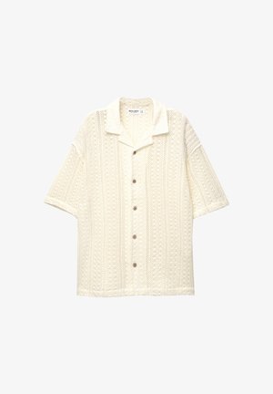 Short-sleeved, collared shirt in cream with a textured knit pattern and five brown buttons down the front.