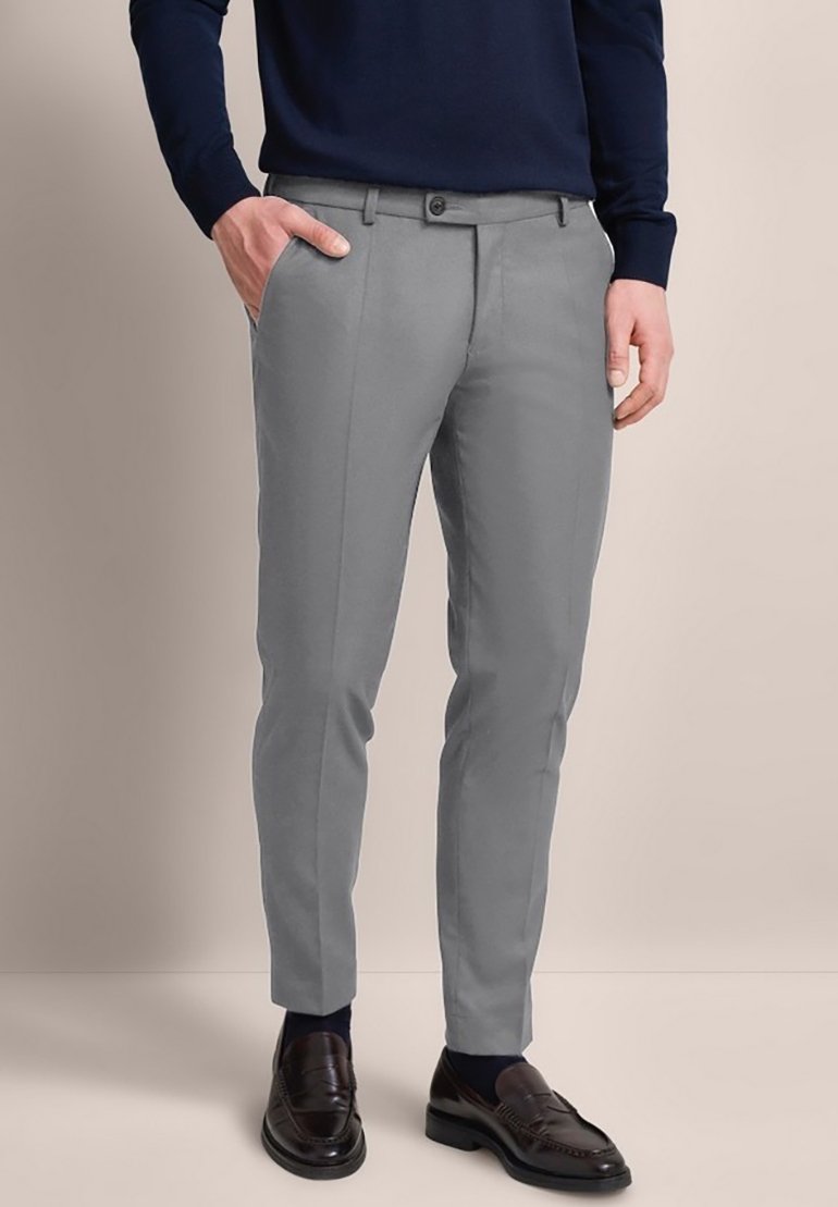 Grau maßgeschneiderte Hose mit slim Fit, flachem Vorderteil und zwei Seitentaschen, kombiniert mit dunklen Slippern und einem marineblauen Pullover.