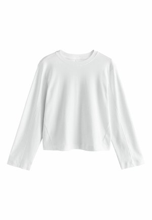 Hvid langærmet cropped top, lavet af glat bomuldsstof. Har en rund halsudskæring og indbyggede ærmer med minimal syning.