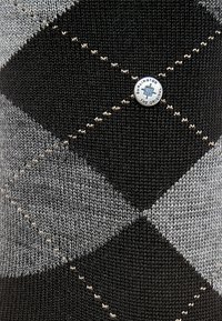 Calcetines de punto con un patrón de argyle en negro, gris y beige, con un botón redondo del logo de Burlington en el centro. Tejido texturizado.