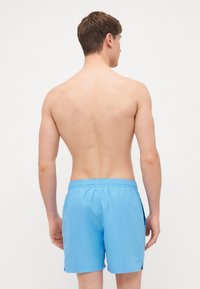 Shorts de bain bleus en tissu léger, dotés d'une taille élastique et de poches latérales, avec une texture lisse et sans motifs visibles.