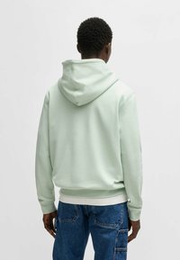 Mint green hoodie with a spacious hood and ribbed hem, made of soft fabric. The back shows a simple design with no visible logos or patterns.