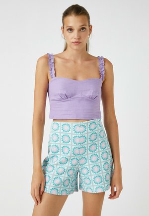 Top corto lila con tirantes rizados y un diseño ajustado, combinado con pantalones cortos de un azul claro con un patrón floral y una cuadrícula.