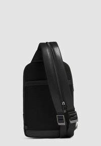 Borsa a tracolla nera con corpo in tessuto testurizzato e dettagli in pelle liscia. Presenta una chiusura con zip e una tracolla regolabile con accessori in metallo.