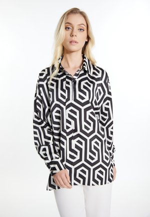 Camicia a maniche lunghe con un pattern geometrico in bianco e nero. Presenta un colletto strutturato, bottoni e una finitura in tessuto liscia e lucida.