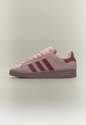 Pink Adidas sneaker med tekstureret materiale, mørk pink striber, snørebånd og sål, vist fra siden på en ensfarvet baggrund.