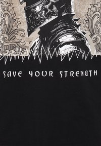 Camiseta negra con un gráfico de armadura de caballero en plateado y blanco. El texto dice "SALVA TU FUERZA" en un tipo de letra negrita y estilizada.
