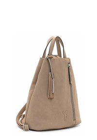 Sac à dos beige perforé avec double poignées supérieures, poche zippée verticale à l'avant, détail pompon et bretelles réglables.