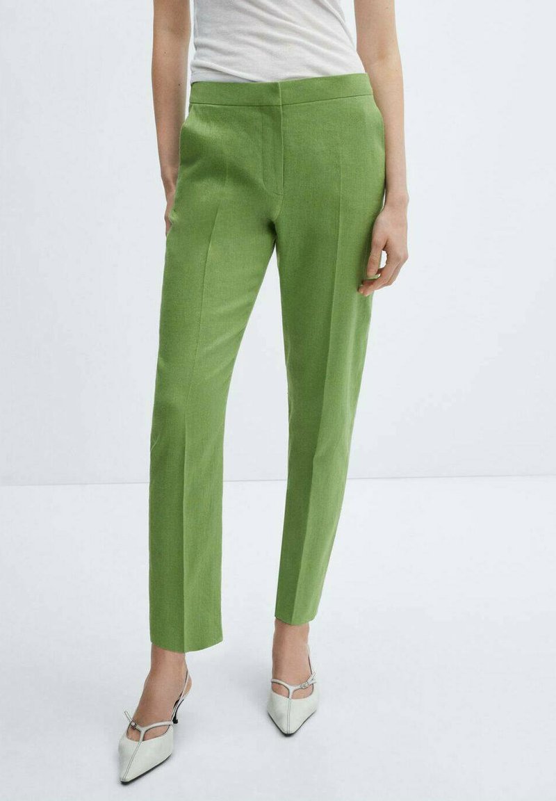 Groene op maat gemaakte broeken met een gladde textuur, rechte pijpen en een hoge tailleband. Gecombineerd met witte puntige hiel schoenen.