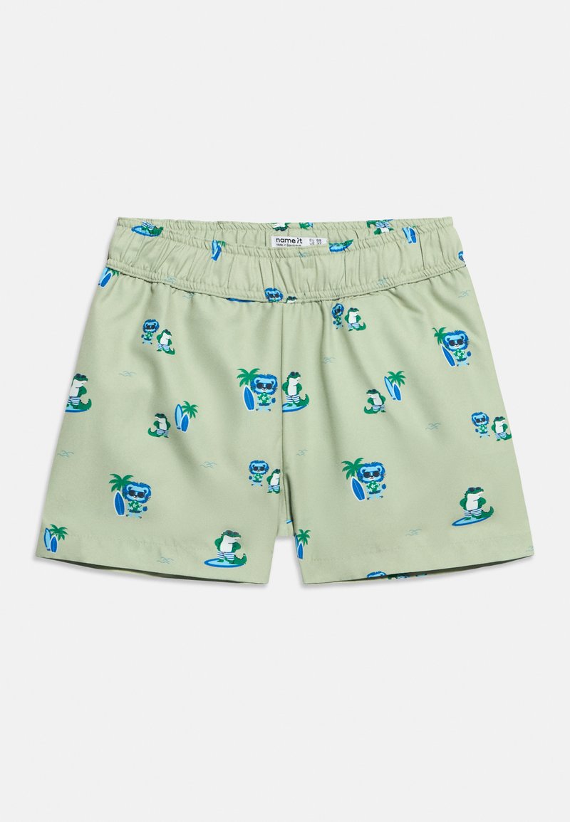Shorts pour enfants vert clair avec taille élastique, illustrés d'animaux de dessin animé bleus et verts faisant du surf et se tenant près de palmiers.