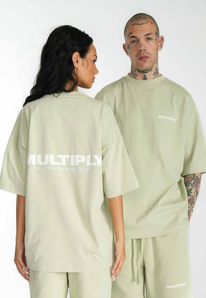 Camiseta de gran tamaño en verde claro hecha de tela suave, con el logo "MULTIPLY" en blanco en la parte posterior, con mangas cortas y cuello redondo.