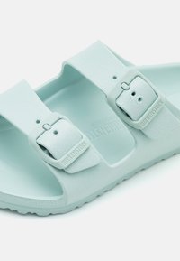 Ανοιχτό μπλε σανδάλια Birkenstock με δύο ρυθμιζόμενες λουρίδες, κατασκευασμένα από μαλακό, υφασματώδες υλικό EVA, με ελική καμπύλη πατούσας για άνεση.