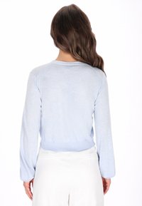 Világoskék, hosszú ujjú pulóver lekerekített nyakkivágással és bordázott szegéllyel. Puha textúrájú, enyhén bő fazonú. Nincsenek látható minták vagy díszítések.