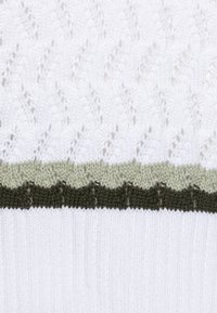 Stickad tröja med en vit kropp och en strukturerad mönster, accentuerad av horisontella ränder i ljusgrön och mörkgrön vid fållen.