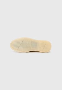 Beiger Schuhsohle mit diagonalen und horizontalen Rillen für besseren Halt, einem transparenten rechteckigen Abschnitt in der Mitte und abgerundeten Kanten.