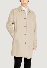 Cappotto beige fino al ginocchio realizzato in tessuto leggero, con colletto, sei bottoni e tasche laterali.