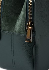 Πράσινη δερμάτινη τσάντα χειρός με υφή, με χρυστό φερμουάρ και σουέντ επένδυση στο εσωτερικό. Λεπτομερής ραφή και γυαλισμένα μεταλλικά στοιχεία.