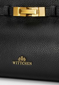 Borsa a mano in pelle nera con finitura texturizzata, caratterizzata da una chiusura in metallo oro e dal logo oro "WITTCHEN" in basso.