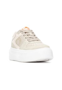 Zapatilla de color beige claro con parte superior de ante y malla, suela de goma blanca, perforaciones sutiles y detalle de marca naranja en la lengüeta.