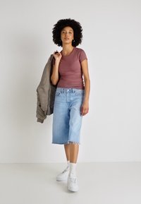 Hele roosa istuv T-särk, hall suurustatud jakk, helesinised kuni põlveni ulatuvad teksapüksid, valged tossud ja valged pahkluudeks sokid. Lihtne disain.