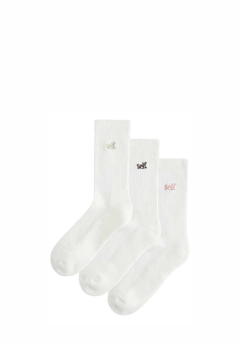 Conjunto de tres calcetines de algodón blanco con textura acanalada. Cada uno presenta un pequeño bordado de "self." en colores variados: beige, marrón y rosa.
