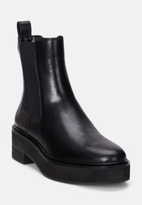 Svart läder Chelsea-boots med rund tå, elastiska sidopaneler och en texturerad plattformssula. Har en dragflik för enkel påtagning.