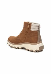 Stivale alla caviglia in suede marrone con colletto in tessuto crema, cerniera laterale e suola in gomma bianca spessa con un motivo di battistrada resistente.