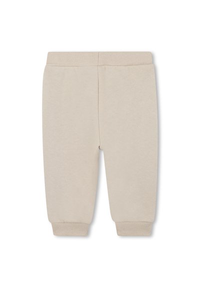 Pantalons de survêtement en coton beige avec taille et poignets côtelés, présentant une texture lisse et un design à jambe fuselée. Pas de poches visibles.