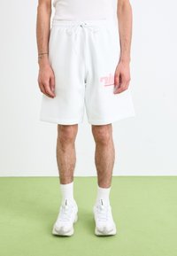 Hvide bomuldsshorts med elastisk talje og snor. Har et pink logo på venstre ben. Bæres med hvide sneakers og sokker.