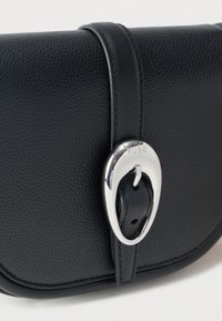 Μαύρη τσάντα χειρός από δερματίνη με υφή, με λείο δερμάτινο λουρί που στερεώνεται με μια λαμπερή ασημένια αγκράφα χαραγμένη με τη λέξη "HUGO".