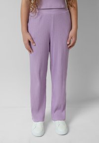 Pantalons côtelés violet clair avec une coupe droite, dotés d'une taille mi-haute et de poches latérales, associés à des baskets blanches.