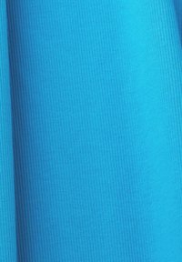 Gros plan d’un tissu côtelé bleu vif montrant des lignes texturées verticales et des ombres subtiles.
