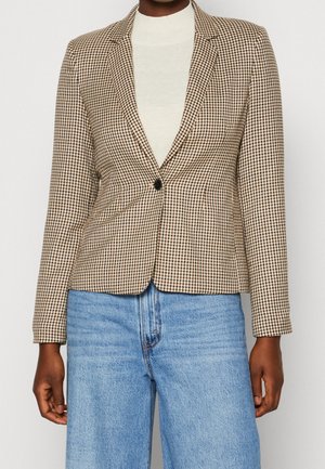 Brązowo-kremowa kraciasta marynarka zapinana na jeden guzik, dopasowana, z długimi rękawami. W połączeniu z jasnoniebieskimi, wysokim stanem dżinsami.