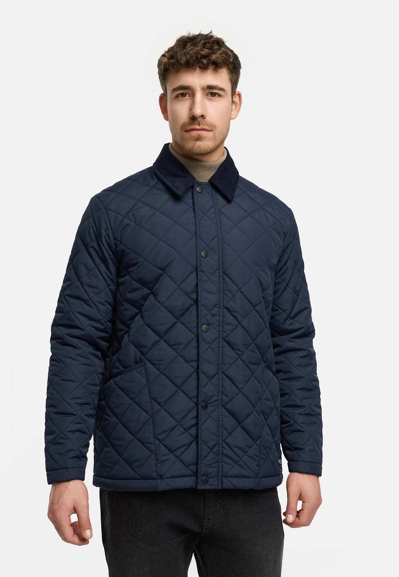 Marineblau gesteppte Jacke mit einem Cordkragen, Druckknöpfen und seitlichen Taschen. Verfügt über ein strukturiertes Rautenmuster und eine lockere Passform.