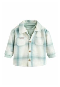 Kergest plaidsest jakk valges ja teal' värvuses, millel on nupuga ees, kaks rinnakotti ja kokku rullitud varrukaid. Pehme kangast tekstuur.