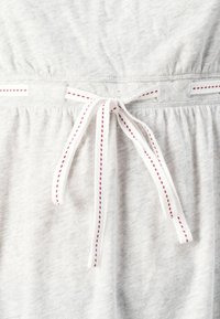 Grijs katoenen kledingstuk met een gathered taille, voorzien van een witte drawstring met rode stiksels. Glad van textuur en eenvoudig van ontwerp.