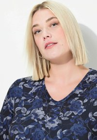 Bloemige V-hals top met een donkerblauwe achtergrond en grijze en blauwe rozenpatronen. Zachte stof met een comfortabele pasvorm.