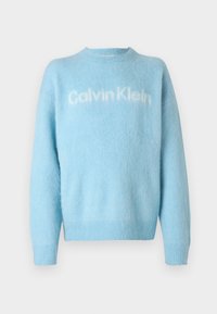 Világoskék bolyhos pulóver hosszú ujjakkal és fehér "Calvin Klein" logóval a mellkason, fehér háttéren.