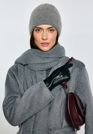 Szary wełniany płaszcz z dopasowanym szalikiem, czarne skórzane rękawiczki oraz bordowa torebka. Szalik ma fakturę, a torebka ma zaokrąglony kształt.