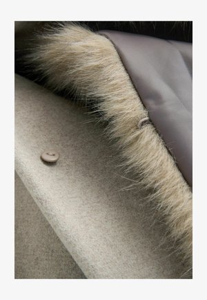 Tessuto di lana beige con un morbido bordo in pelliccia sintetica lungo il bordo, presenta una chiusura a bottone rotondo di colore taupe chiaro. Fodera interna liscia.
