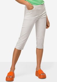 Witte cropped broek met een gladde textuur, elastische tailleband en zijzakken. Gecombineerd met feloranje platform sandalen.