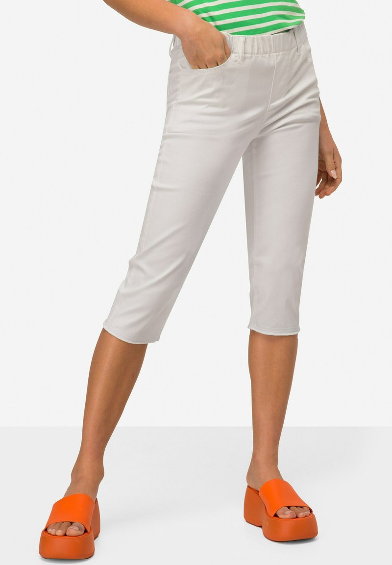 Witte cropped broek met een gladde textuur, elastische tailleband en zijzakken. Gecombineerd met feloranje platform sandalen.