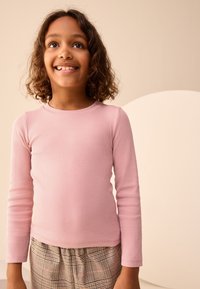 Top de manga larga de color rosa claro con tejido acanalado, combinado con pantalones de cuadros estampados. Textura suave, cuello redondo y mangas ajustadas. Diseño simple y casual.