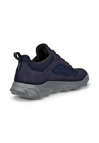 Tummansininen urheilukenkä, jossa on samettinen ja verkkomateriaali päällinen, tekstiilitonninen harmaa pohja ja vetotuli kantapäässä helpompaa pukemista varten.