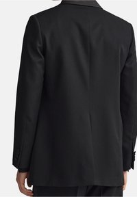Blazer nero in tessuto liscio, con due bottoni ai polsini e colletto a punta. Presenta una schiena pulita senza chiusure o dettagli visibili.