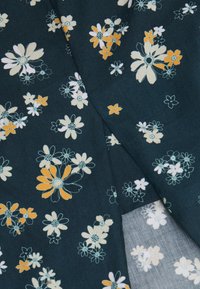 Tessuto a motivo floreale con fiori bianchi, arancioni e blu su uno sfondo verde petrolio scuro, con una texture morbida e liscia.