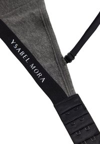 Sostén gris con un acabado de tela suave, correas negras ajustables y una banda negra con "YSABEL MORA" en letras blancas.