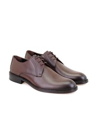 Chaussures en cuir marron avec une finition lisse, bout arrondi et un système de laçage à cinq œillets ; semelles en caoutchouc noir et détails de couture minimaux.