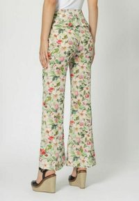 Pantalones de pierna ancha con estampado floral sobre un fondo beige claro, que presentan patrones florales en tonos rosas, rojos y verdes, complementados por un diseño de cintura alta.